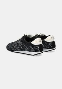 Zapatillas negras con embellishments de rhinestone, acentos blancos, diseño de bajo corte y una suela texturizada. Marca en el talón en dorado.