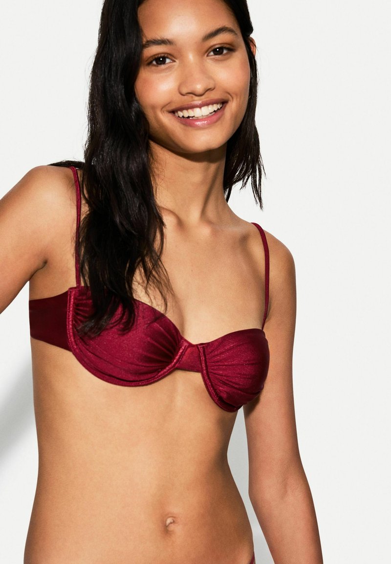 Maroon bikini top with a smooth, shiny texture; features underwire and gathered fabric at the center; thin adjustable straps.