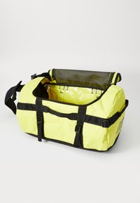 Yellow duffel bag with black straps, features a mesh top panel, sturdy zippers, and multiple buckles for secure closure.