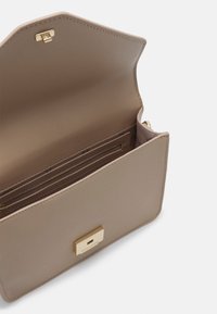 Pochette en cuir camel avec fermoir rectangulaire doré, ouverte pour montrer une poche intérieure zippée et un compartiment, aucun objet à l’intérieur, design minimaliste.