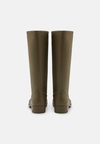 Botas de borracha verdes à prova d'água com uma textura suave, design alto e detalhes em costura amarela. Solas planas e sem hardware visível.