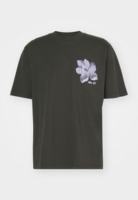 T-shirt noir à manches courtes avec un motif de fleur abstraite à rayures blanches et le texte "NN. 07" sur la poitrine gauche.