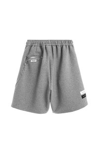 Pantalones cortos de sudadera grises de algodón con cintura elástica, bolsillo lateral con cremallera, detalle de cadena y dos parches de tela con texto cerca del dobladillo.