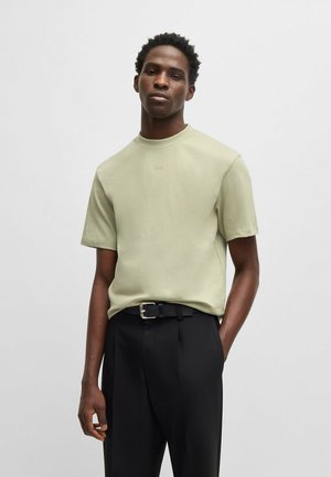 Light green t-shirt with a crew neck and short sleeves, made of soft fabric. Paired with tailored black trousers featuring a belt.