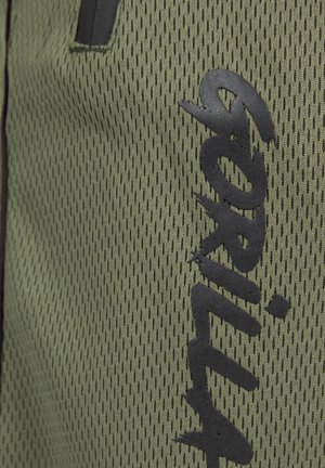 Groen gaasstof met een gestructureerd patroon. Bevat een gedurfde zwarte logo, contrasterende accenten en een algeheel lichtgewicht ontwerp.