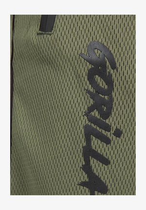 Groen gaasstof met een gestructureerd patroon. Bevat een gedurfde zwarte logo, contrasterende accenten en een algeheel lichtgewicht ontwerp.