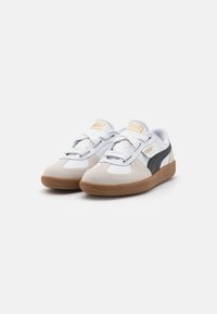 Weiße und graue Wildledersneaker mit schwarzen Akzenten, einer strukturierten Gummisohle und auffälligen weißen Schnürsenkeln, die ein markiertes Zungenetikett tragen.