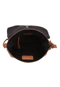 Crna platnena torba s tamnosmeđim kožnim remenom i detaljima. Zatvaranje na patentni zatvarač, unutarnji džep, kožna oznaka. Jednostavan, funkcionalan dizajn.