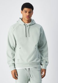 Felpa con cappuccio verde chiaro, con lacci neri, maniche raglan, tasche a marsupio e un piccolo logo sul maniche. Materiale strutturato.