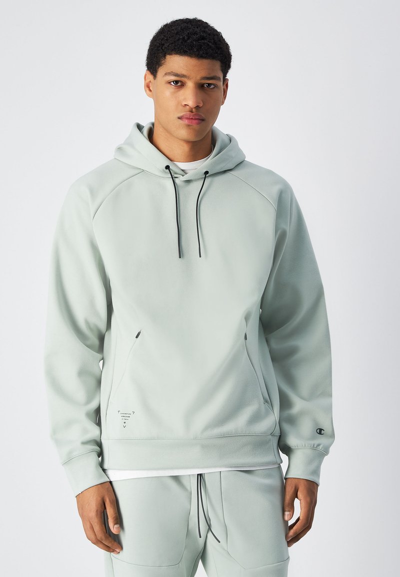 Felpa con cappuccio verde chiaro, con lacci neri, maniche raglan, tasche a marsupio e un piccolo logo sul maniche. Materiale strutturato.