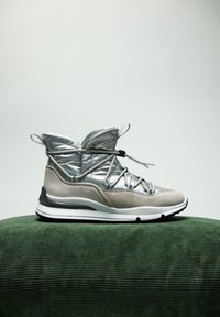 Zapatilla alta en gris claro y plateado con una parte superior acolchada, diseño con cordones, suaves acentos de ante y una suela de goma blanca.