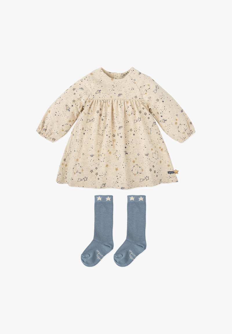 Vestido de algodón en beige con estampado de estrellas y cohetes, combinado con calcetas azules hasta la rodilla con detalles de estrellas blancas.