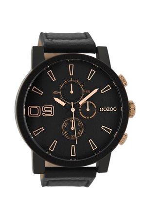Montre noire avec un cadran noir texturé, indices et accents en or rose, trois sous-cadrans, et un bracelet noir mat. Marque : OOZOO.