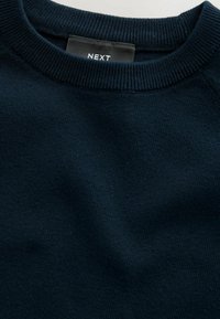 Pull bleu marine avec un col rond côtelé. Fabriqué en un tissu doux et texturé. Étiquette visible avec le logo "NEXT".