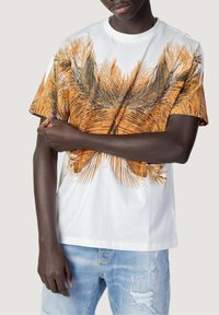White cotton t-shirt featuring a large orange and black palm leaf print across the front. Short sleeves and relaxed fit design.