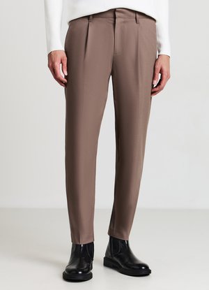 Braune maßgeschneiderte Hose mit glatter Textur, flacher Vorderseite und knöchellangem Schnitt, kombiniert mit schwarzen Stiefeletten.