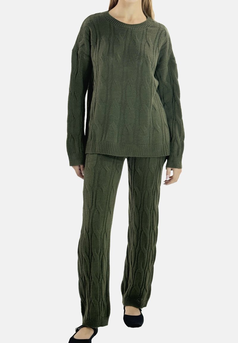 Olivengrøn strikket sweater og matchende bukser med kabelstrikket mønster. Sweateren har rund hals og løs pasform.