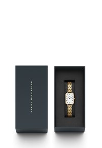 Guldklocka med en rektangulär vit urtavla, blå visare och romerska siffror. Utrustad med ett guldmetallarmband, presenterad i en mörkblå låda.