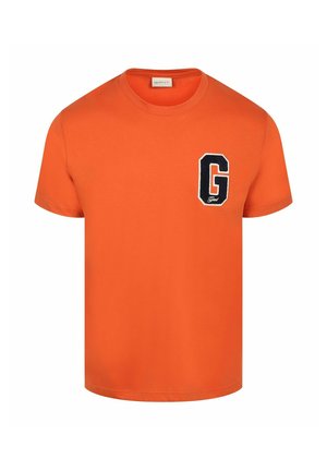 Oranje T-shirt met korte mouwen, een ronde hals en een grote zwart-witte letter G patch op de linkerborst.