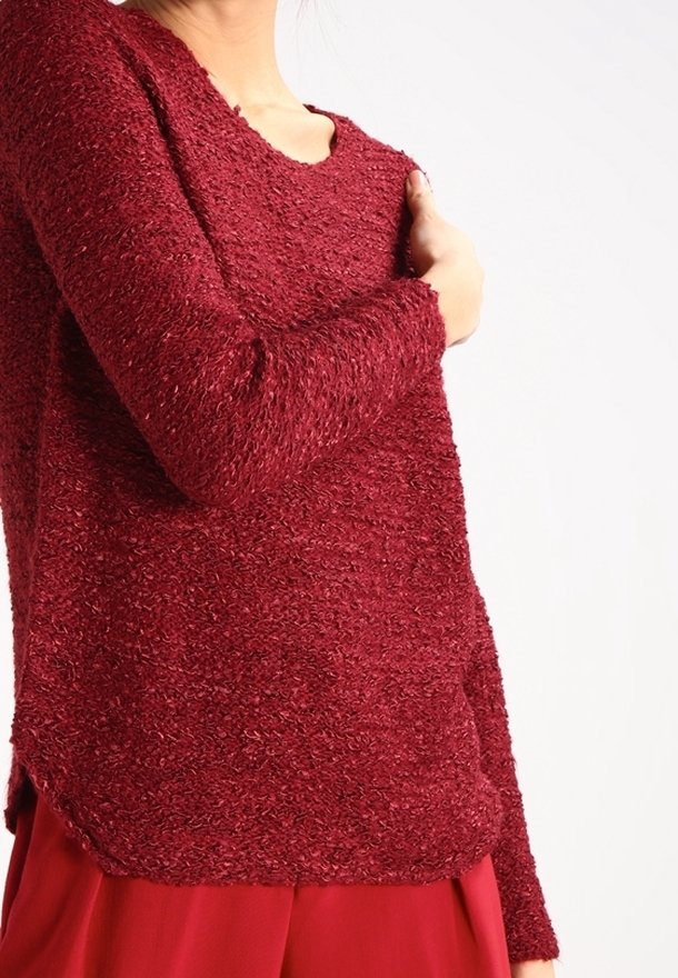 Maglione rosso a trama con maniche lunghe, caratterizzato da una vestibilità leggermente ampia e un ampio scollo. Il tessuto appare morbido e peloso.