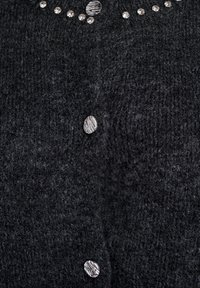 Črna pletena cardigan jakna z teksturirano tkanino, šestimi okrogli gumbi in okrasnimi elementi iz prozornih ter vzorčnih kamenčkov ob ovratniku.