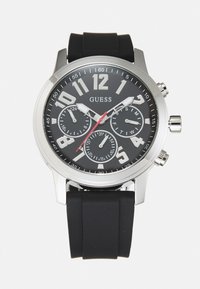 Orologio con cinturino in gomma nera, cassa in tonalità argento, quadrante nero, grandi numeri bianchi e tre sottodial. Accenti rossi e pulsanti cromati.