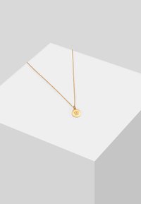 Collier doré avec un pendant circulaire, présentant un motif d'empreinte de paw et de petites pierres gemmes, suspendu à une chaîne fine.