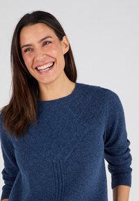 Maglione lavorato a maglia di un blu profondo con motivo a diamante testurizzato, scollo rotondo e maniche arrotolate. Materiale morbido e accogliente con una vestibilità comoda.