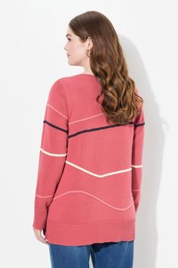 Różowy sweter z dzianiny z kontrastowymi poziomymi i ukośnymi paskami w odcieniach kremowym i granatowym. Charakteryzuje się luźnym krojem, okrągłym dekoltem i ściągaczem na dole.
