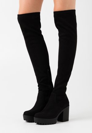 Schwarze Overknee-Stiefel aus weichem Veloursleder, mit klobigem Absatz, Plateausohle und seitlichem Reißverschlussdetail.