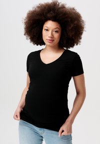 Sort ribbet kortærmet t-shirt med v-udskæring. Blød tekstur, tætsiddende form, stylet med lyseblå jeans.