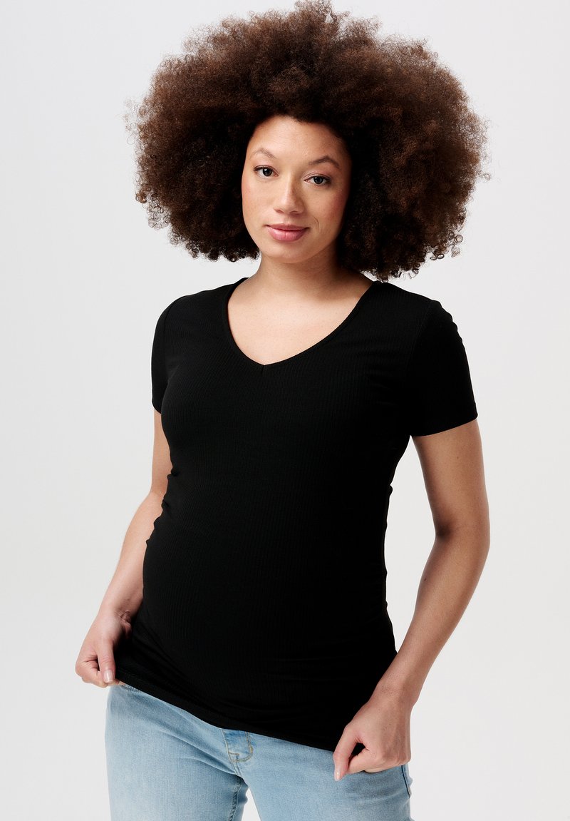 Sort ribbet kortærmet t-shirt med v-udskæring. Blød tekstur, tætsiddende form, stylet med lyseblå jeans.