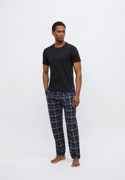 Černé tričko s krátkým rukávem spojené s tmavě modrými kostkovanými pyžamovými kalhotami s modrými a bílými linkami, vyrobené z lehké látky, bosý.