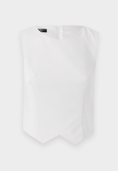 White sleeveless top with a rounded neckline, fitted shape, and a unique zigzag hem. Crafted from smooth fabric with a concealed back zipper.