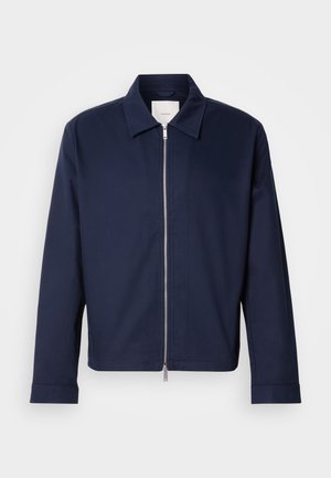 Veste bleu marine en tissu lisse, dotée d'une fermeture éclair, d'un col pointu et de manches longues. Design minimaliste sans motifs apparents.