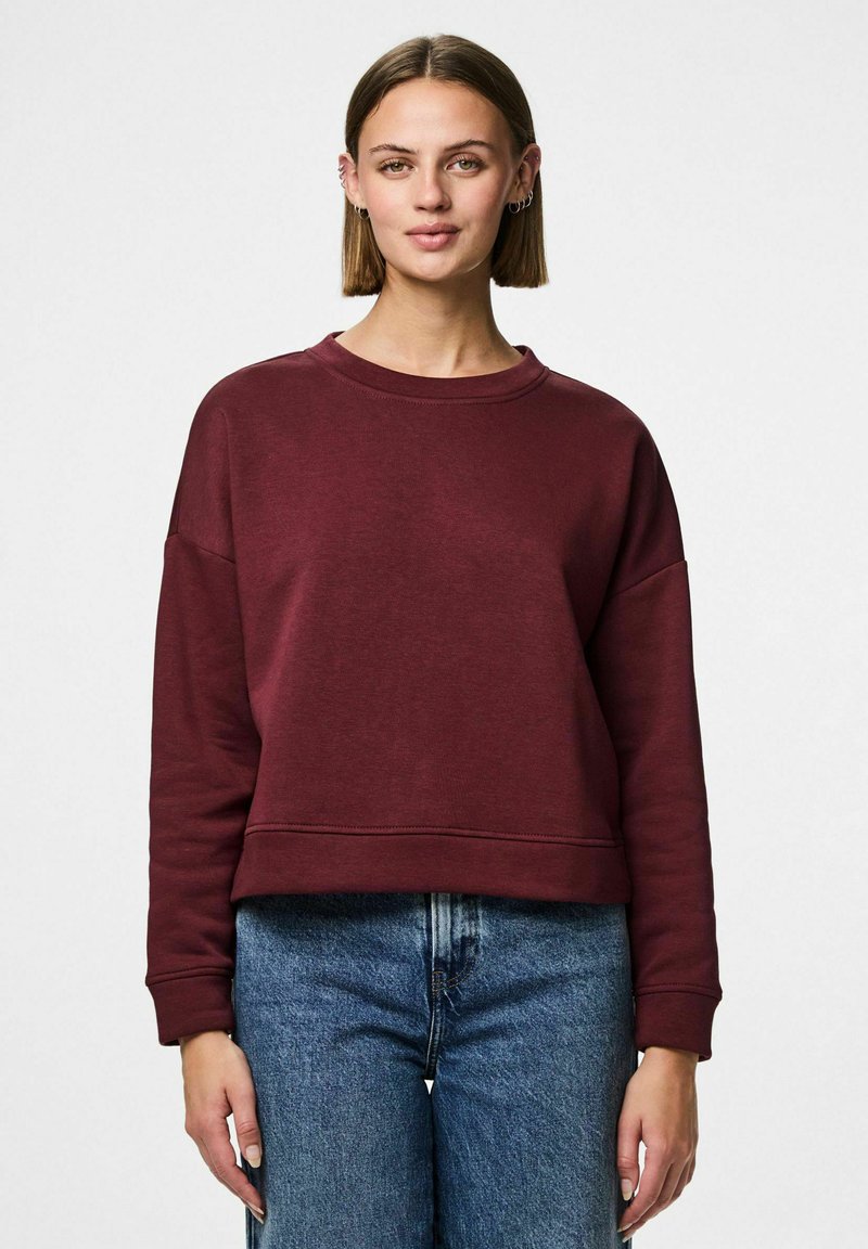 Burgunderfarget cropped hettegenser med rund halsutskjæring, lange ermer og myk tekstur, kombinert med høyt liv blå denim jeans.