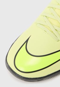 Fotbalová obuv Nike v jasně žluté barvě s hladkým povrchem, vyznačující se výrazným černým logem Swoosh a kontrastní tmavou podrážkou.