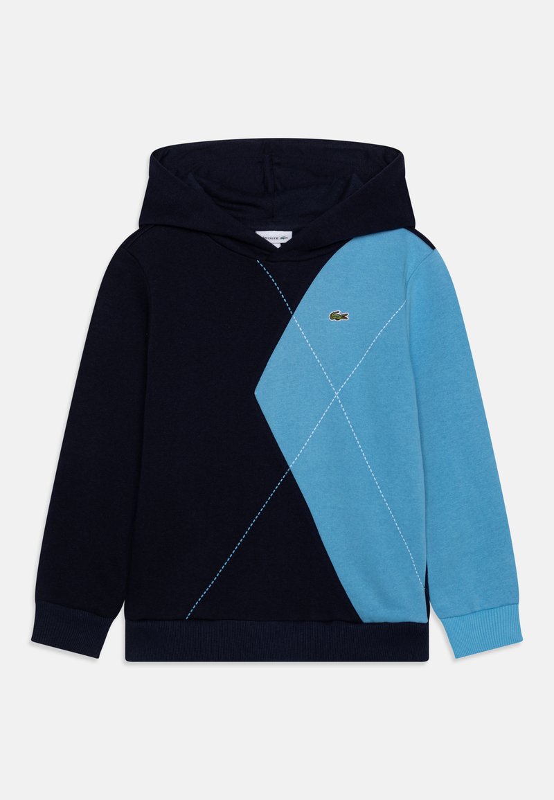 Sweatshirt à capuche présentant un design en blocs de couleurs bleu marine et bleu clair, avec un motif en losange, des poignets côtelés et un petit logo Lacoste.