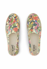TOMS slip-on shoes with a cream background, featuring a colorful floral pattern. Textured canvas upper and elastic side panels for fit.
