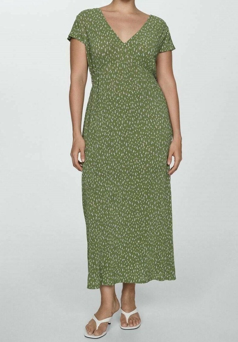 Robe longue verte à motif blanc imprimé, manches courtes, encolure en V et texture lisse. Portée avec des tongs blanches.