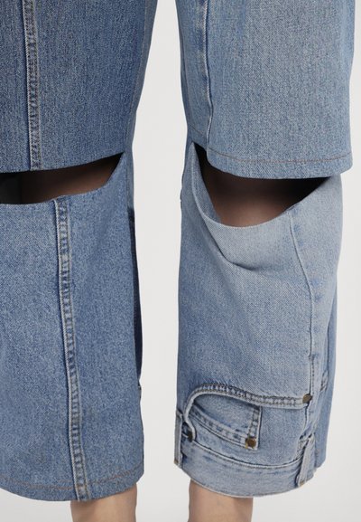 Denim culottes vaaleansinisinä, joissa on leikkauksia ja kontrastiväriset ompeleet. Varustettu sivutaskuilla ja messinkisillä yksityiskohdilla.