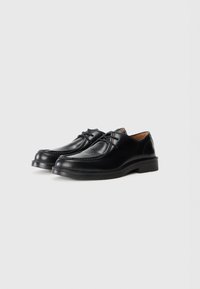 Black leather shoes featuring a smooth texture, rounded toe, subtle stitching detail, and a low heel design.
