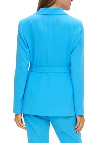 Blazer ajusté bleu clair avec des manches longues et une taille ceinturée. Tissu lisse, revers crantés et un design de dos structuré.