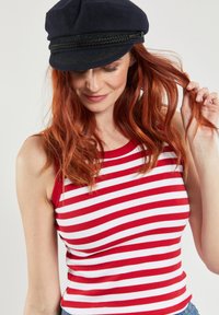 Rood-wit gestreepte tanktop van ribstof, gecombineerd met een marineblauw pet met een gestructureerde band en een vlakke klep.