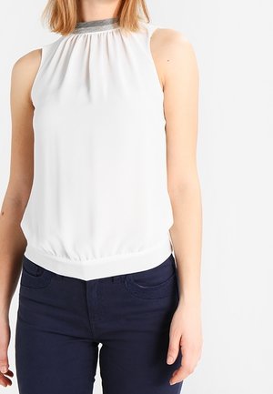 Biała bluzka bez rękawów z szarym kołnierzykiem, noszona z ciemnoniebieskimi spodniami, przedstawiona na stojącej osobie od ramion do bioder.