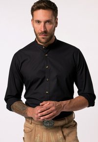 Musta napitettava paita nostettavalla kauluksella, jossa on kultaiset napit ja pitkät hihat. Materiaali on sileä ja istuva.
