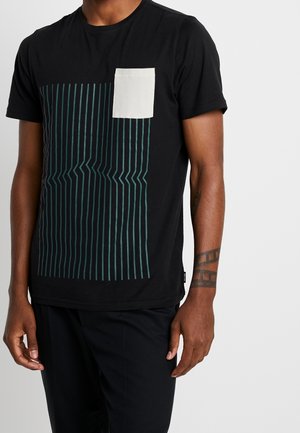 Camiseta de algodón negra con un diseño de rayas en color teal en el frente; cuenta con un pequeño bolsillo en el pecho de color crema y mangas cortas.