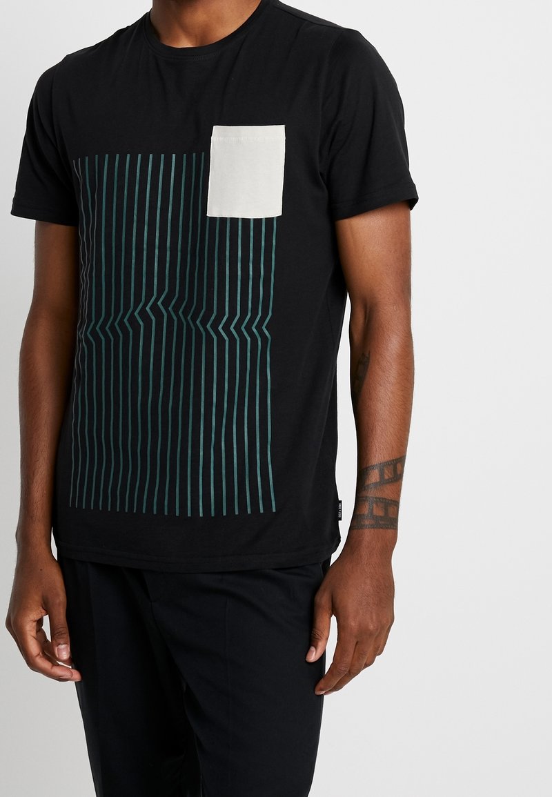Sort bomulds t-shirt med et teal stribet design på forsiden; har en lille cremefarvet brystlomme og korte ærmer.