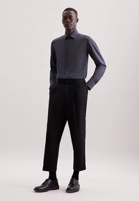 Ciemnoszara koszula na guziki o gładkiej fakturze, zestawiona z czarnymi spodniami o wysokim stanie. Zestaw uzupełniają eleganckie czarne buty.