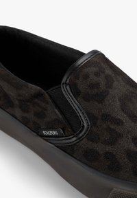 Zapatilla slip-on con parte superior de ante en estampado de leopardo negro y gris oscuro, panel lateral elástico negro, suela negra y pequeña etiqueta de la marca Scalpers.